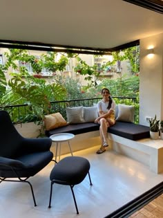 a woman sitting on top of a white bench next to a black chair and table