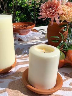 two candles sitting on top of a table next to vases with flowers in them