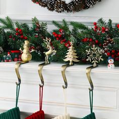 three christmas stockings hanging from hooks on a mantel