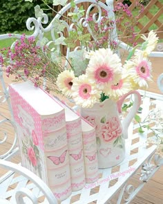 flowers and books are sitting on a bench with a book in the shape of a teapot