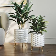 two white planters sitting on top of a wooden floor