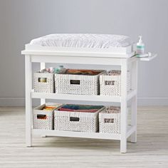 a white changing table with baskets underneath it