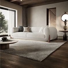 a white couch sitting on top of a wooden floor in a living room next to a window