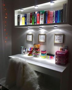 a white desk topped with lots of books and office supplies next to a wall mounted book shelf