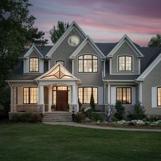 a large gray house with lots of windows and lights on it's front door