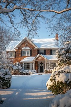 a house with snow on the ground and trees in front of it that are covered in snow