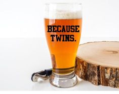 a glass of beer sitting on top of a table next to a piece of wood