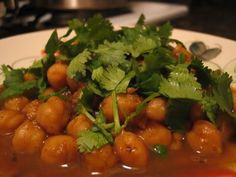 a white plate topped with lots of food on top of a wooden table covered in sauce