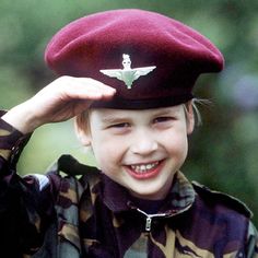 a young boy wearing a red beret smiles at the camera while holding his hat over his head