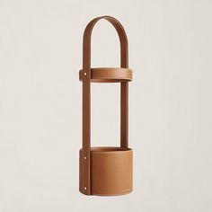 a tan leather cylinder holder with two straps hanging from it's sides, on a white background