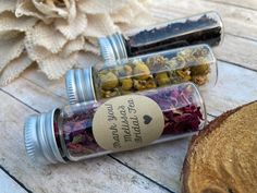 three glass jars filled with different types of flowers on top of a wooden table next to a slice of bread