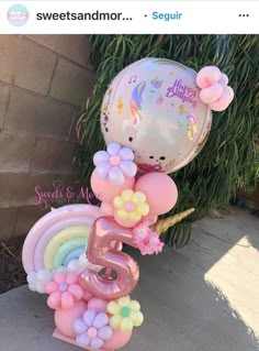 a number five balloon with balloons attached to it and some flowers on the top, sitting in front of a tree