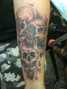 a man's arm with three skulls on it and one is holding the other hand