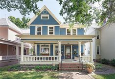 a blue and white house with porches in the front yard on a sunny day