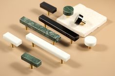 an assortment of marble and brass knobs on a beige background with black, white, and green accents