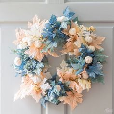 a wreath is hanging on the door with blue and pink flowers in front of it