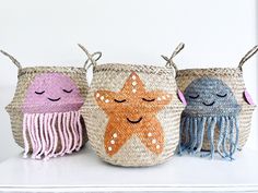 three baskets with different designs on them sitting on a shelf next to each other, one has a starfish and the other is a jellyfish