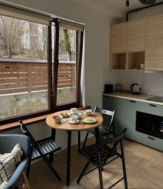 a small table with plates of food on it in front of an open kitchen window