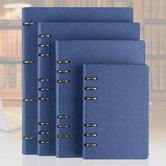 three blue binders are next to each other in front of a bookshelf