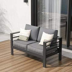 a gray couch sitting on top of a wooden floor next to a glass wall with sliding doors