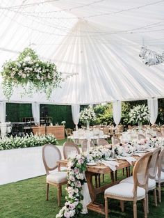 an outdoor tent with tables and chairs set up for a wedding reception in the grass