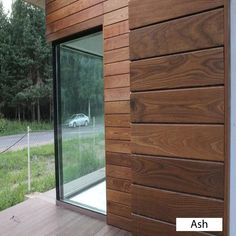 a car is parked on the side of a wooden building next to a grassy field