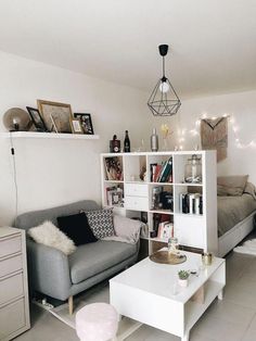 a living room filled with furniture next to a white table and bookshelf on top of a hard wood floor