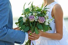 a bride holding a bouquet of flowers in her hands while the groom holds his arm