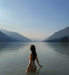 a woman in a body of water with mountains in the background