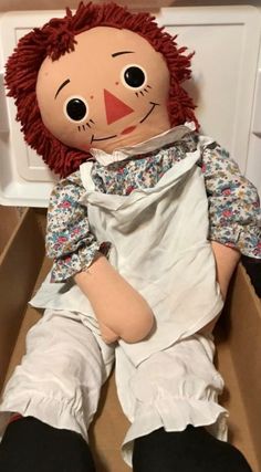 a ragged doll sitting in a cardboard box