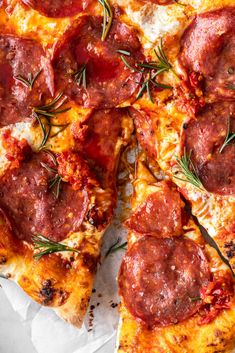 a pizza with pepperoni, cheese and rosemary sprigs on it's crust