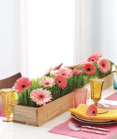 the table is set with pink flowers in gold vases and place settings for dinner