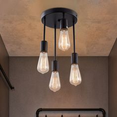 three light bulbs hanging from the ceiling in a room with an iron pipe and metal frame