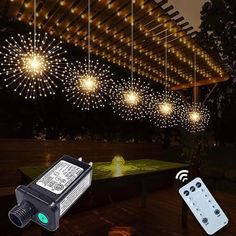 an outdoor string light with remote controls on the table and in the background is a firework display