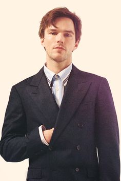 a man in a suit and tie posing for the camera with his hand on his pocket