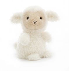 a white stuffed sheep sitting up against a white background