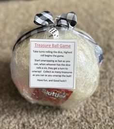 a plastic bag filled with dices on top of a carpeted floor next to a sign that reads, treasures ball game