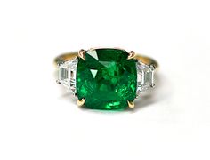 an emerald and diamond ring with three baguets on the side, set in yellow gold