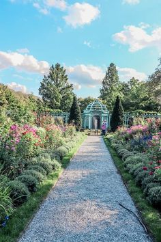 a pathway in the middle of a garden with lots of flowers and trees around it