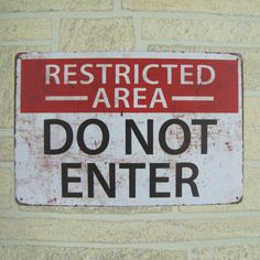 a red and white sign that says restricted area do not enter on a brick wall