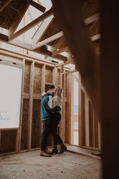 a man and woman hug in the middle of a room with wood framing around them