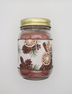 a mason jar with pine cones, cinnamons and other things in it on a white background