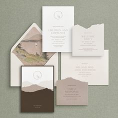 the wedding stationery is laid out on top of each other, with mountains in the background