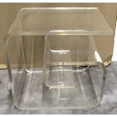 two clear plastic tables sitting on top of a carpeted floor next to a wall