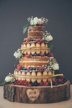 a wedding cake made out of fruit and flowers on top of a tree stump with the word love written below it