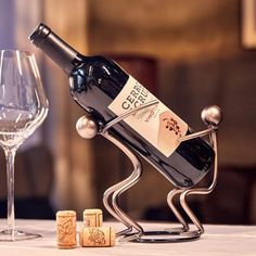 a wine bottle holder sitting on top of a table next to a glass and corks