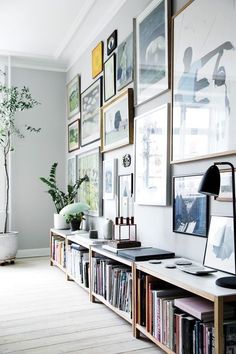 a living room filled with lots of books and pictures on the wall next to a window