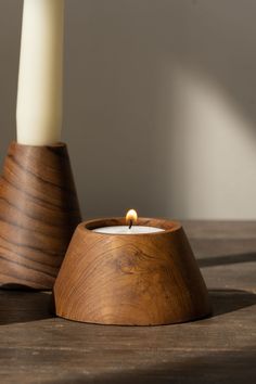 a wooden candle holder sitting on top of a table with a lit candle in it