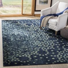 a living room with a blue rug and white chair in front of a large window