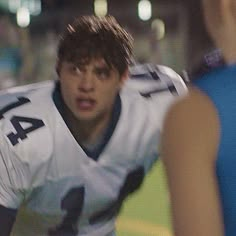 a young man in a football uniform is talking to an official